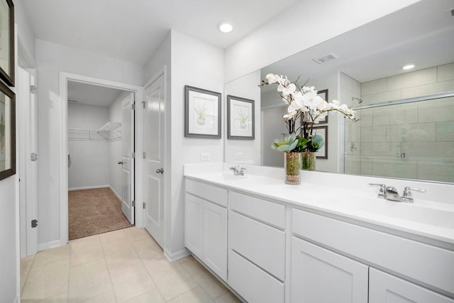 bathroom with a shower with door, vanity, and tile patterned floors