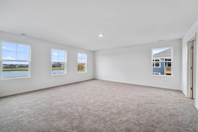 carpeted empty room featuring a water view