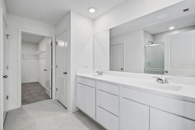 bathroom with a shower with door, vanity, and tile patterned floors