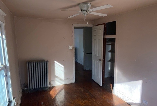 unfurnished room featuring radiator heating unit, dark wood-type flooring, and ceiling fan