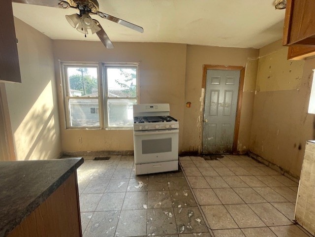 kitchen featuring white gas range, light tile patterned floors, and ceiling fan