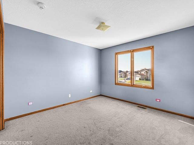 carpeted empty room featuring a textured ceiling