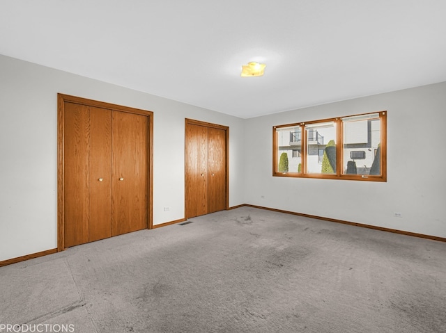 unfurnished bedroom with light carpet and multiple closets