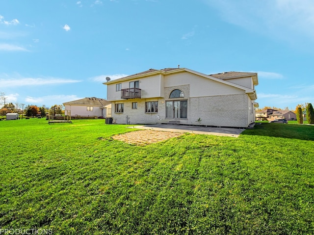 back of property featuring a lawn, a patio area, a balcony, and central AC unit