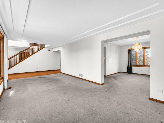 unfurnished living room featuring a notable chandelier and carpet floors