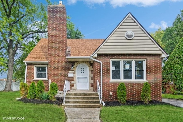 view of front facade featuring a chimney, a front lawn, and brick siding