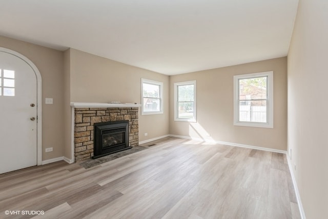 unfurnished living room with a fireplace, light wood-type flooring, and plenty of natural light