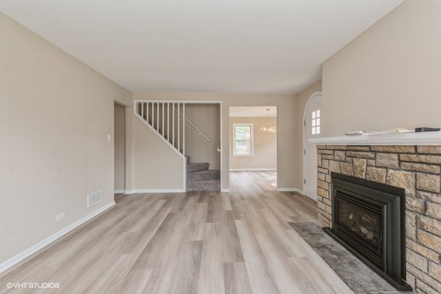 unfurnished living room featuring light hardwood / wood-style flooring, a chandelier, and a fireplace