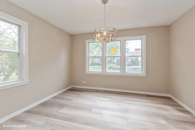 unfurnished room featuring light hardwood / wood-style flooring and an inviting chandelier