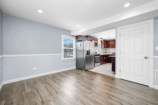 kitchen featuring appliances with stainless steel finishes, tasteful backsplash, and light hardwood / wood-style floors