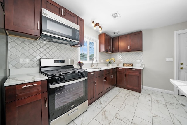 kitchen featuring backsplash, appliances with stainless steel finishes, sink, and light stone counters