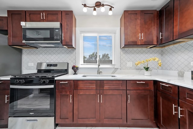 kitchen with appliances with stainless steel finishes, sink, light stone counters, and backsplash