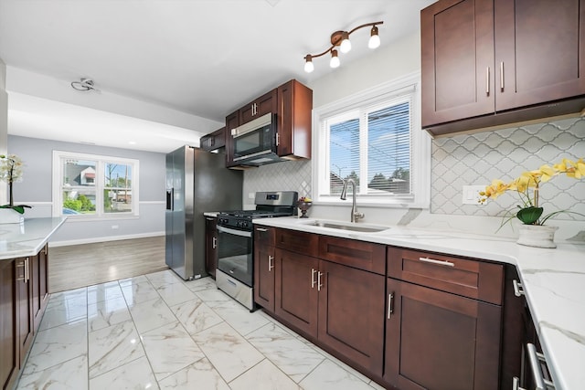 kitchen with sink, light stone countertops, stainless steel appliances, and plenty of natural light