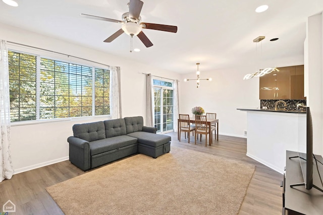 living room featuring ceiling fan with notable chandelier and dark hardwood / wood-style floors