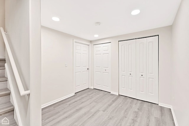 unfurnished bedroom featuring two closets and light wood-type flooring