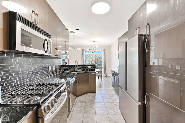 kitchen featuring hanging light fixtures, stainless steel appliances, sink, light tile patterned flooring, and tasteful backsplash