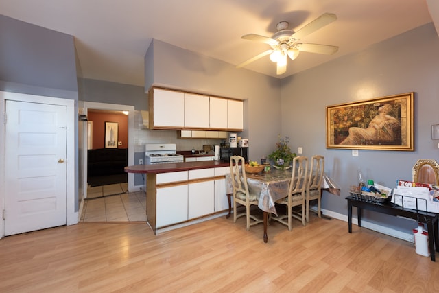 kitchen with light hardwood / wood-style flooring, backsplash, white range with gas stovetop, white cabinets, and ceiling fan