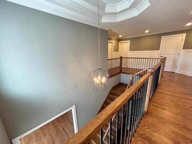 stairway featuring ornamental molding, a notable chandelier, and hardwood / wood-style flooring