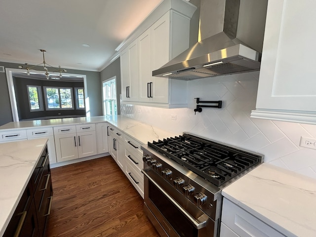 kitchen with wall chimney exhaust hood, white cabinetry, high end stove, and tasteful backsplash