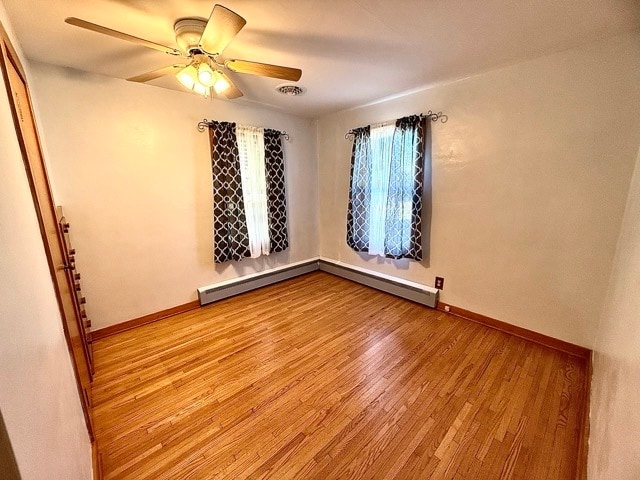 empty room with a baseboard heating unit, light wood-type flooring, and ceiling fan