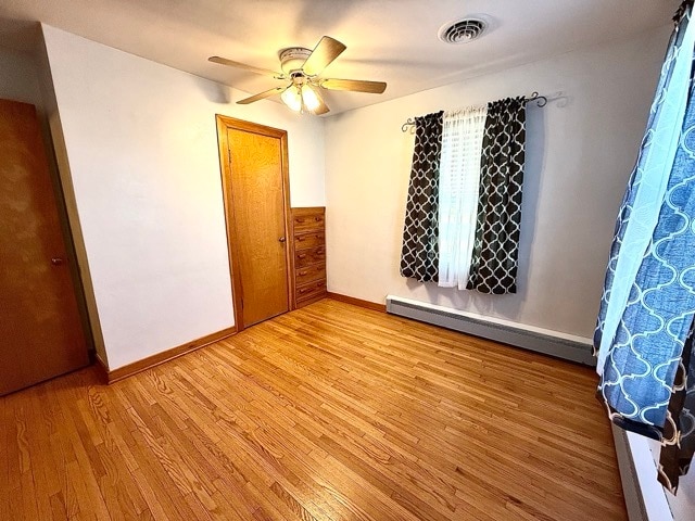 spare room with baseboard heating, light hardwood / wood-style floors, and ceiling fan