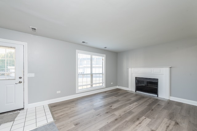 unfurnished living room with light hardwood / wood-style flooring and a healthy amount of sunlight