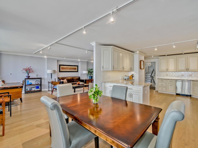 dining area with rail lighting, crown molding, and light hardwood / wood-style flooring