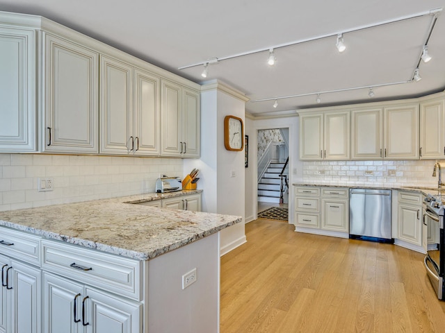 kitchen featuring track lighting, light hardwood / wood-style flooring, stainless steel appliances, backsplash, and light stone countertops