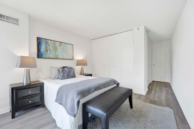 bedroom featuring a closet, a textured ceiling, and hardwood / wood-style flooring