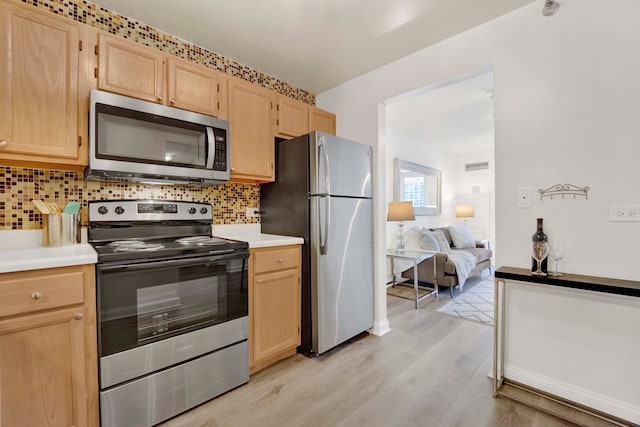 kitchen with light brown cabinetry, appliances with stainless steel finishes, light hardwood / wood-style flooring, and backsplash