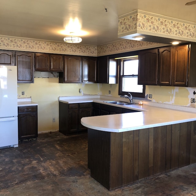 kitchen with white refrigerator, dark brown cabinetry, kitchen peninsula, and sink