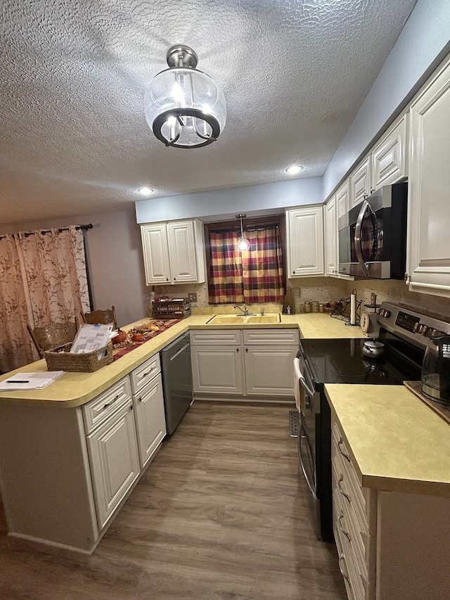 kitchen with kitchen peninsula, white cabinetry, dark wood-type flooring, and stainless steel appliances