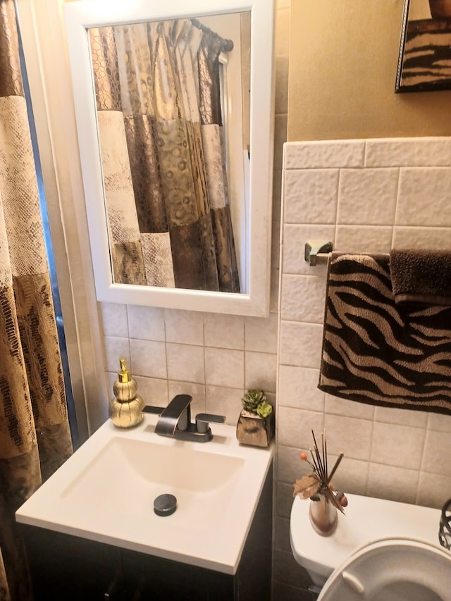 bathroom featuring vanity, toilet, decorative backsplash, and tile walls