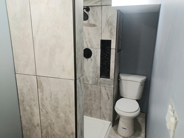 bathroom featuring tiled shower, toilet, and tile patterned floors