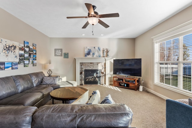 carpeted living room featuring ceiling fan and a stone fireplace