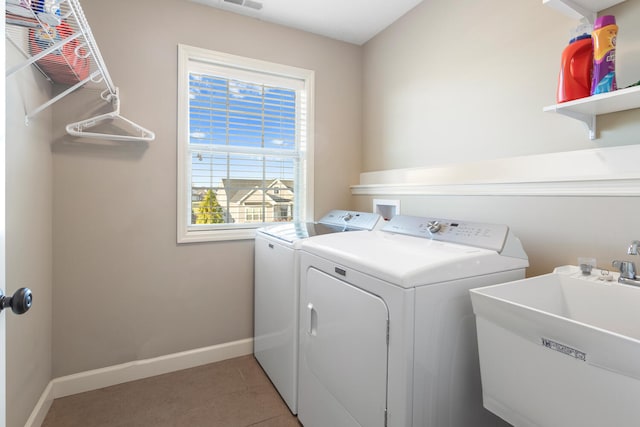 clothes washing area with light tile patterned floors, washing machine and dryer, and sink