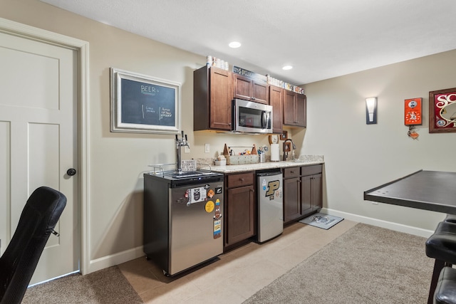 kitchen with dark brown cabinetry, stainless steel appliances, and light tile patterned floors