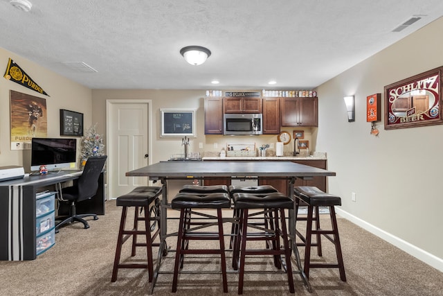 interior space with a breakfast bar area, dark colored carpet, and a textured ceiling