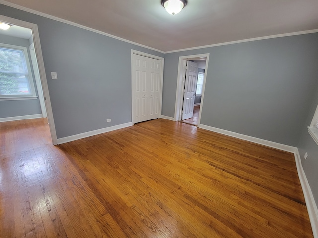 unfurnished bedroom featuring ornamental molding, light hardwood / wood-style flooring, ensuite bathroom, and a closet