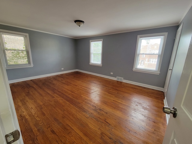 empty room featuring ornamental molding and hardwood / wood-style floors