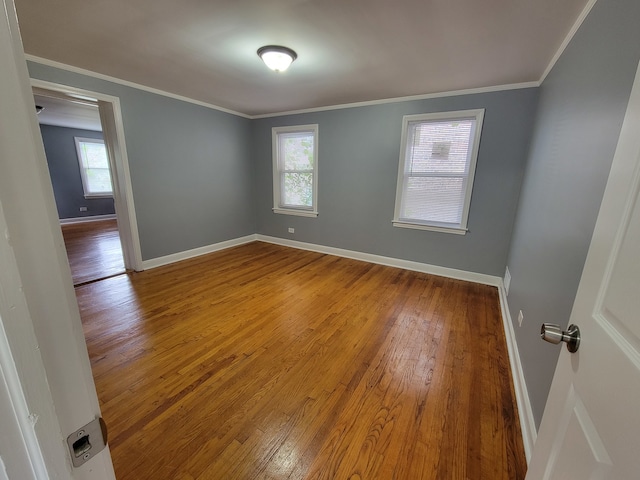 empty room with ornamental molding, hardwood / wood-style floors, and plenty of natural light