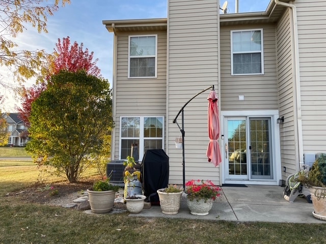 rear view of house featuring a lawn, central air condition unit, and a patio