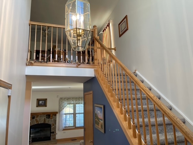 stairway featuring a notable chandelier and a fireplace