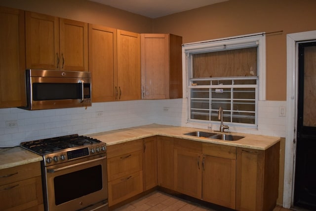 kitchen with backsplash, stainless steel appliances, sink, and light tile patterned floors