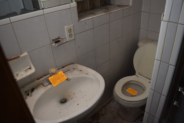 bathroom featuring toilet, sink, and tile walls