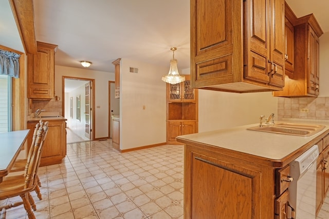 kitchen with tasteful backsplash, white dishwasher, sink, and pendant lighting