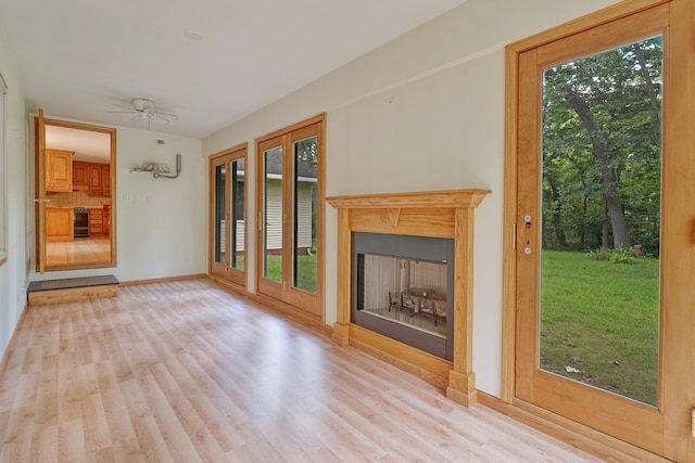 unfurnished living room with light hardwood / wood-style floors, ceiling fan, and a wealth of natural light