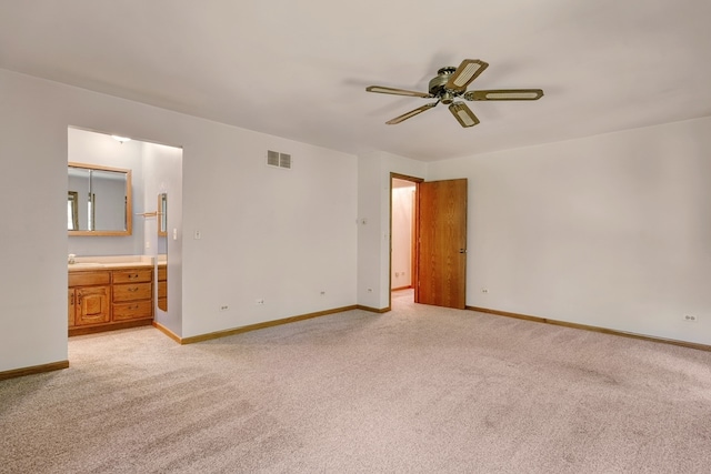 unfurnished bedroom with connected bathroom, sink, light carpet, and ceiling fan