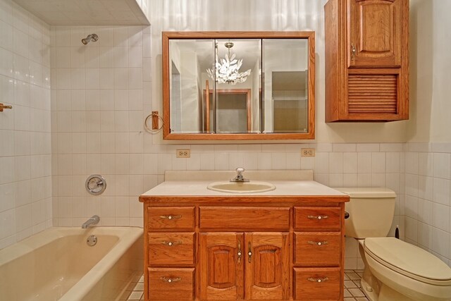 full bathroom featuring tiled shower / bath, tile walls, toilet, vanity, and tile patterned floors