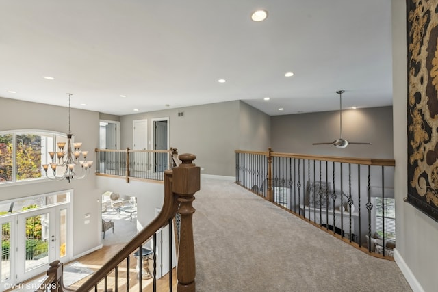 corridor featuring a chandelier and light colored carpet